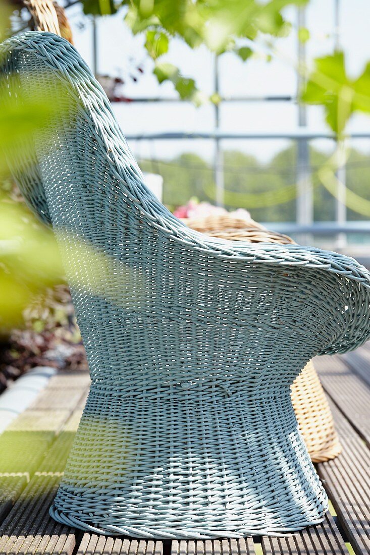 Hellblauer Rattansessel auf Holzterrasse