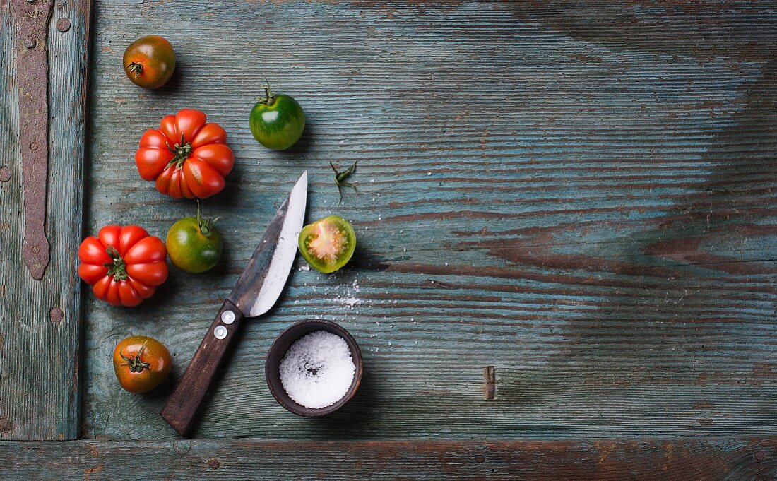 Green and red tomatoes with salt and a knife