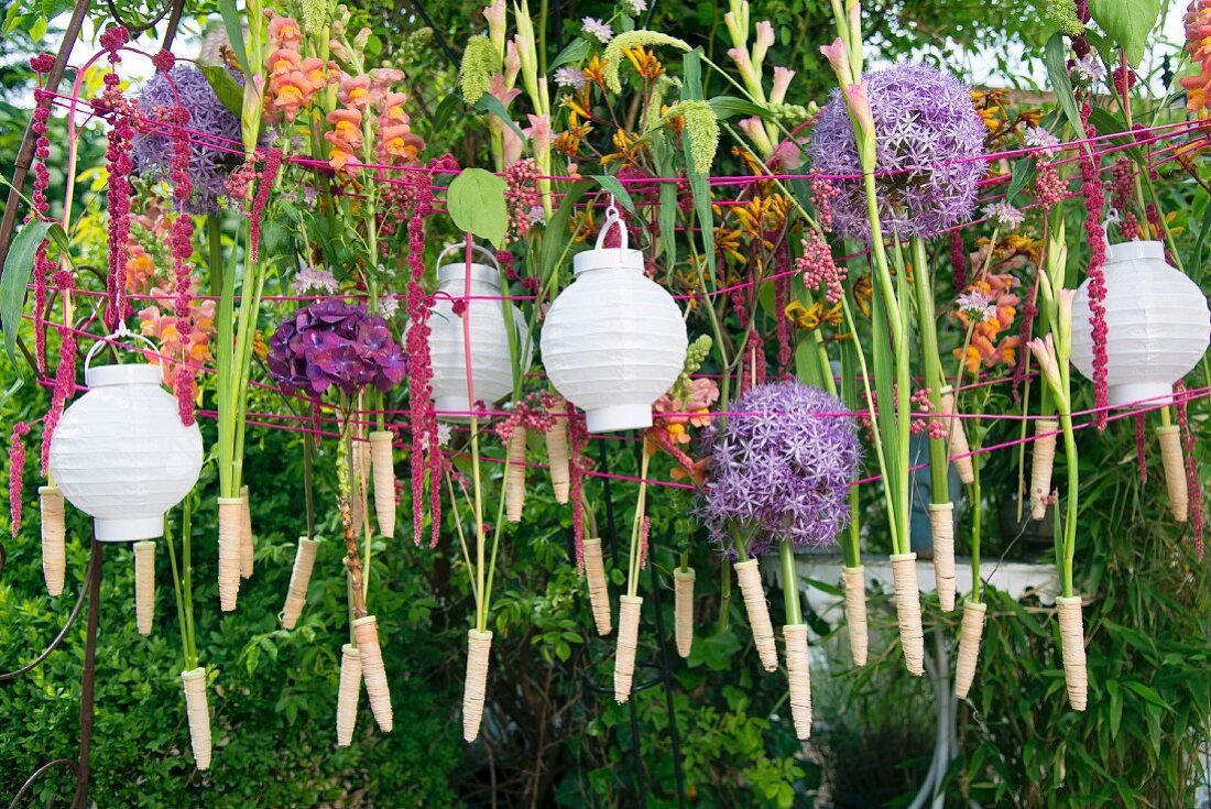 Wäscheleine mit weissen Lampions und Blumen im Garten