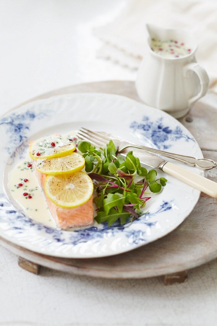 Poached salmon fillet with a pink pepper sauce, lemons and salad