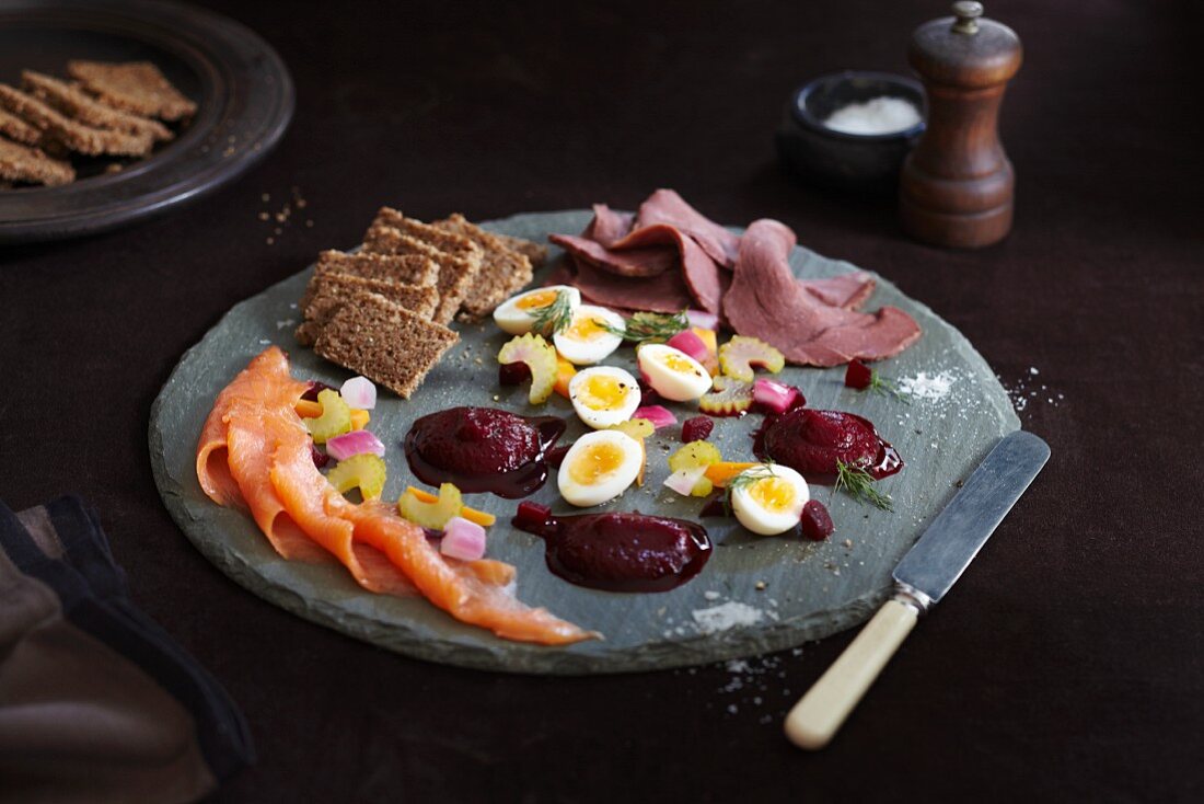 Scandinavian appetiser platter with smoked salmon, beetroot purée, rye bread, boiled eggs and cold beef slices