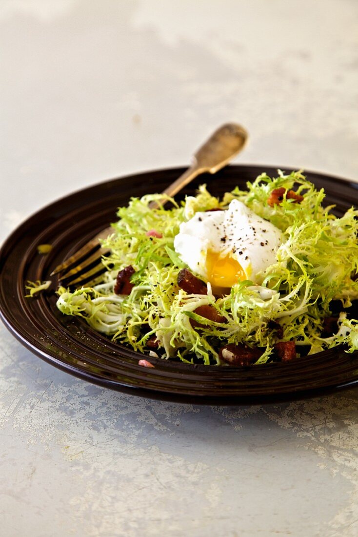 Salade Lyonnaise mit Frisee, pochiertem Ei und knusprigem Speck (Lyon, Frankreich)