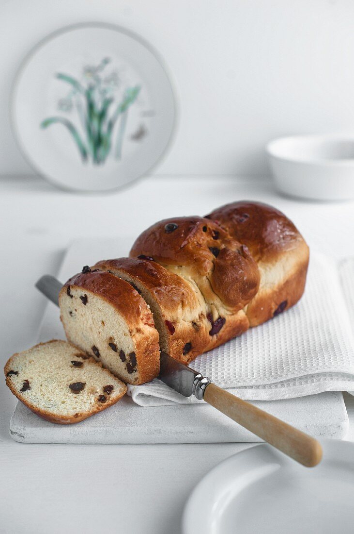 Angeschnittener Rosinenkuchen auf weißem Schneidebrett mit weißem Küchentuch