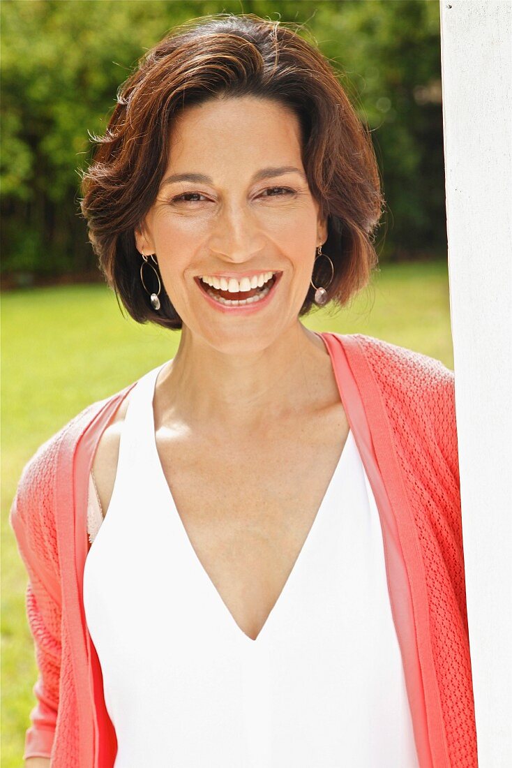 Dark-haired woman wearing top and cardigan in garden