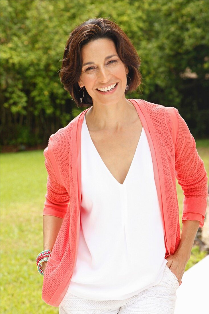 Dark-haired woman wearing top and cardigan in garden