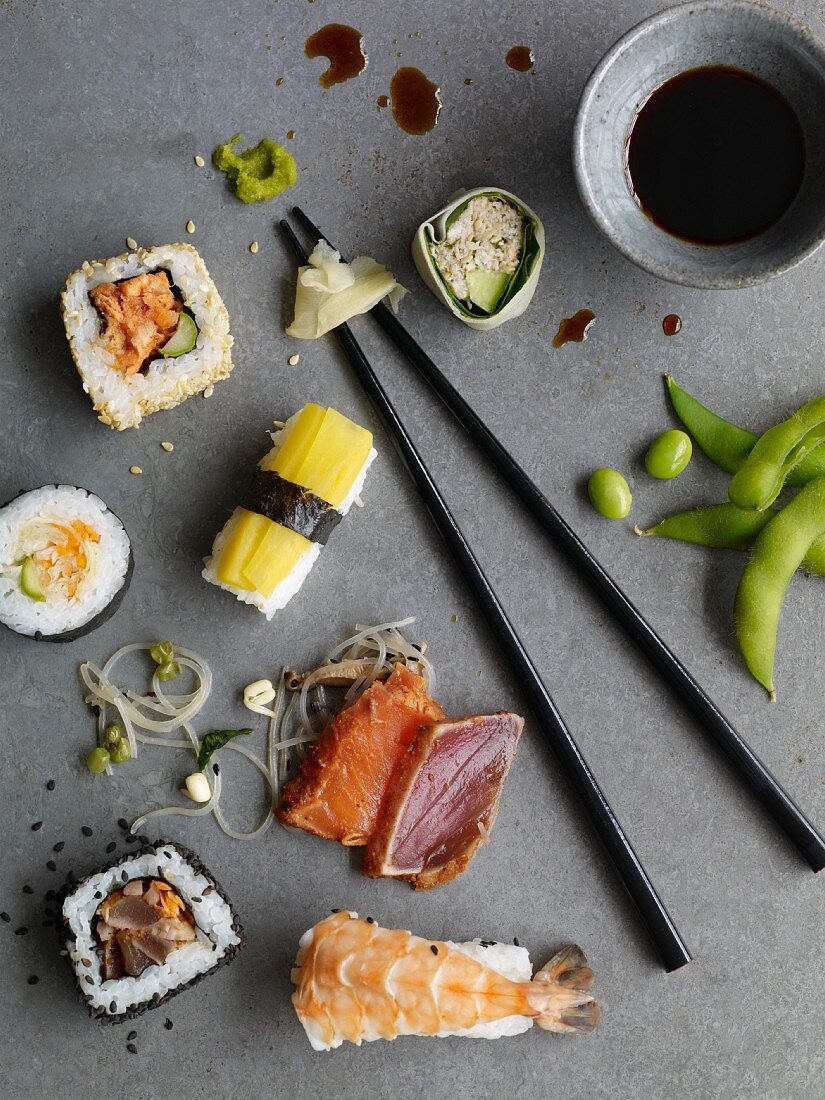 Nigiri sushi, California rolls, maki sushi and sashimi on a grey surface