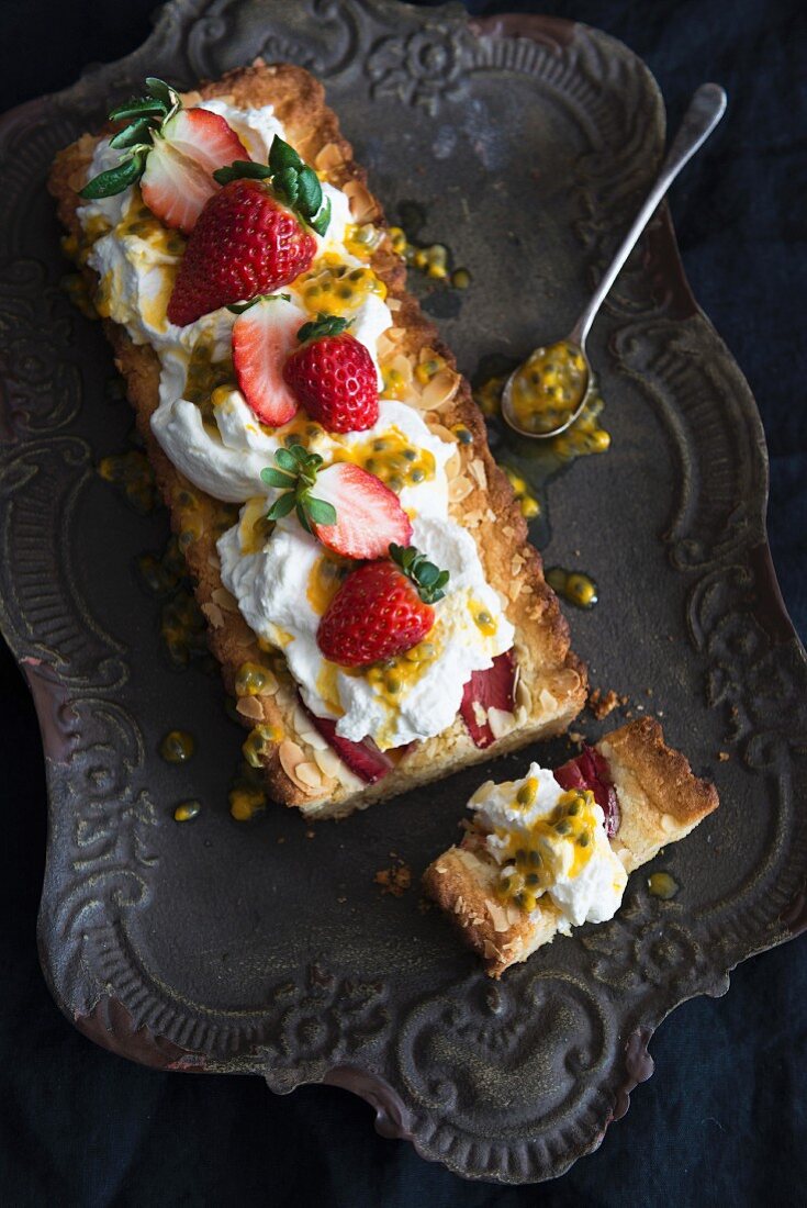 Frangipane-Kuchen mit Erdbeeren und Passionsfruchtsauce, angeschnitten