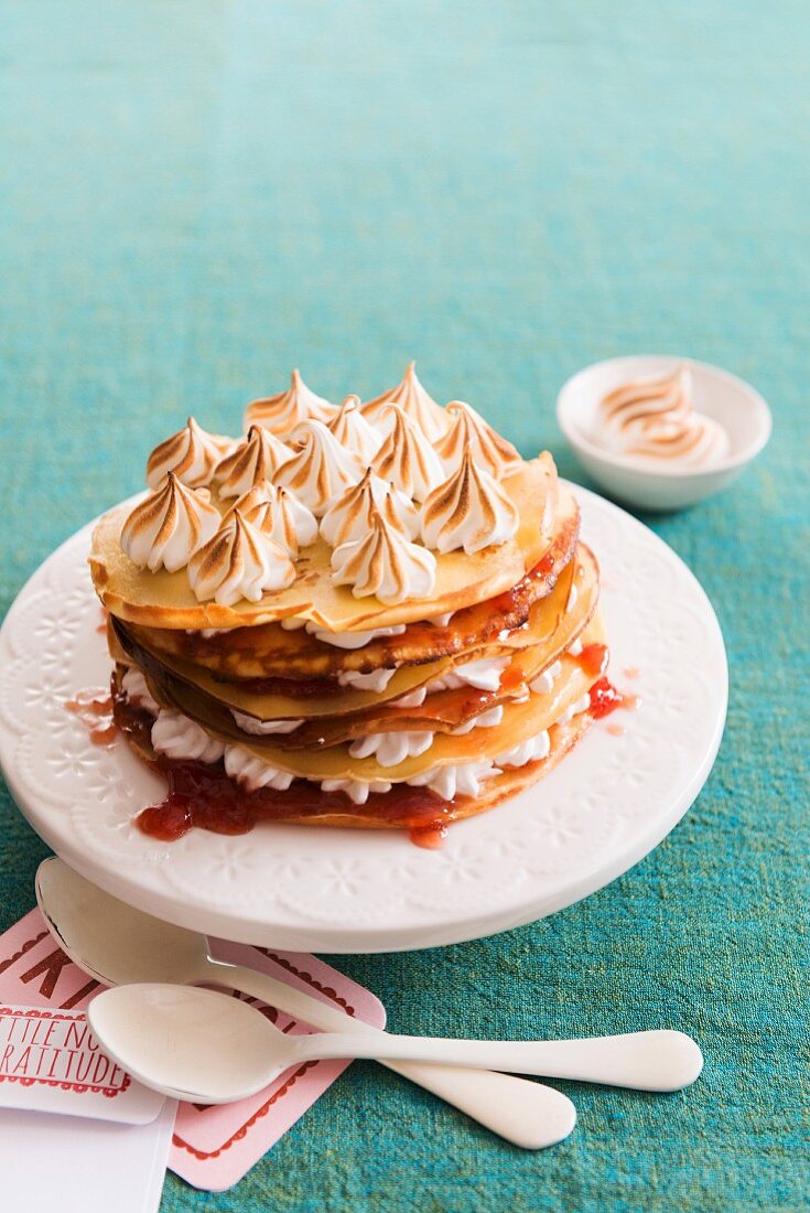 A stack of pancakes with jam and meringue