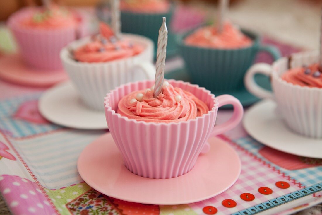 Pink cupcakes with birthday candles served in cups