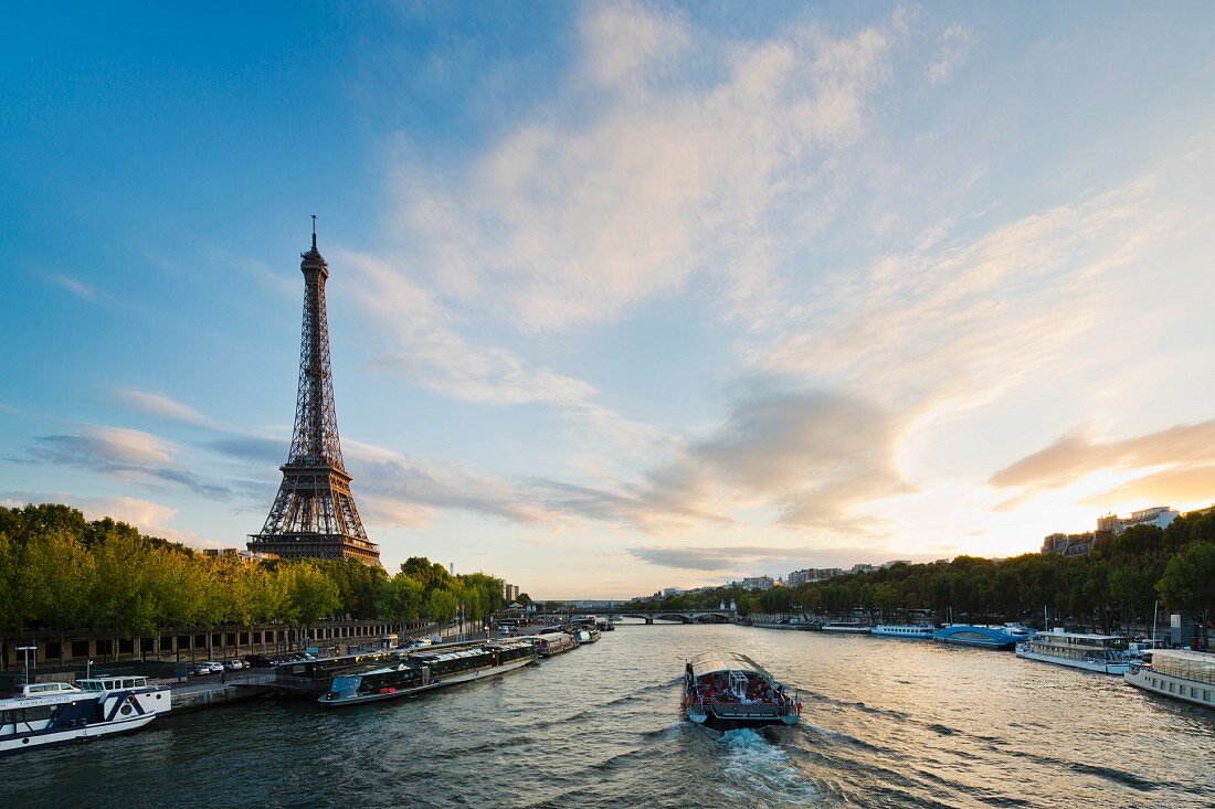 An imposing view of the River Seine with the Eiffel Tower on the left and a sunset to the right