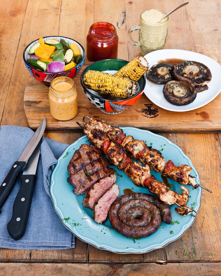 Corn cobs and meat, chicken tikka skewers and barbecued steaks at The Backyard Grill Lounge, Sea Point, South Africa