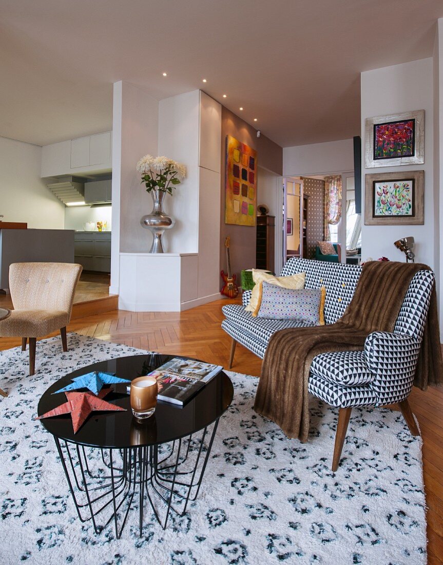 Delicate coffee table and black and white, fifties-style couch in open-plan interior