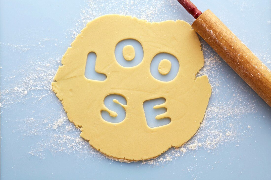 Rolled biscuit dough with the word LOOSE cut out of it