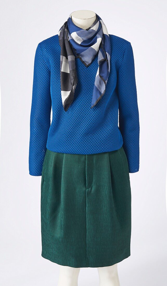 A blue jumper, a checked scarf and a midi skirt on a headless mannequin