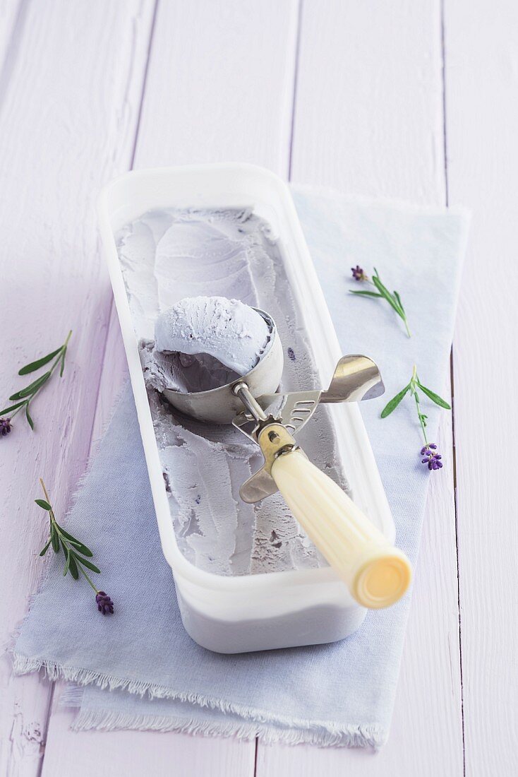 Lavender ice cream in a container with an ice cream scoop