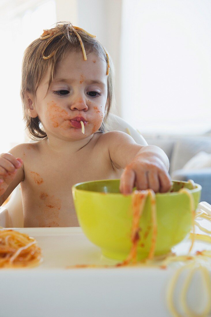 Girl eating spaghetti with tomato sauce