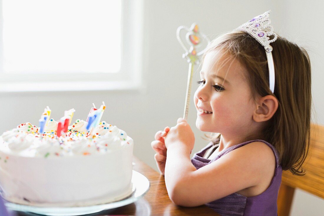 A little girl looking at a birthday cake