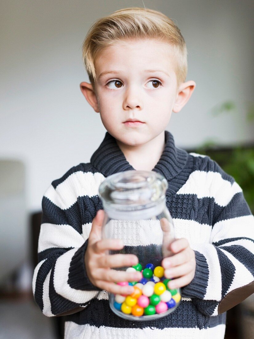 Junge hält Glas mit Bonbons