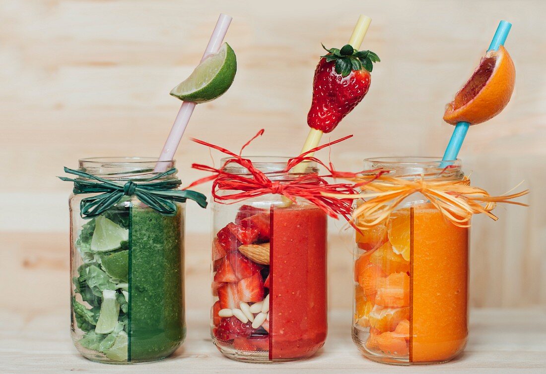 Three different smoothies (red, green and orange) with fruit and vegetables