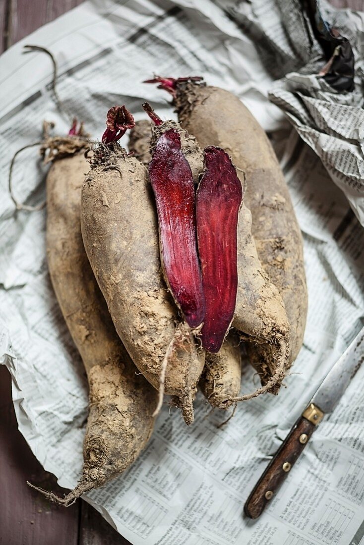 Long beetroots, whole and halved, on newspaper