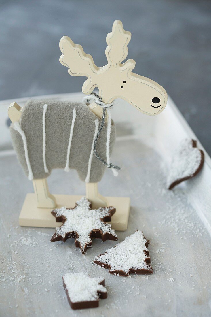 Verschiedenes Schokoladenkonfekt mit Kokosflocken und hölzerner Elchfigur zu Weihnachten