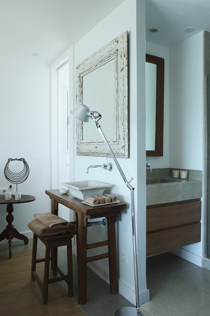 Tolomeo standard lamp next to rustic washstand with countertop basin; additional sink in niche with drawers in base cabinet