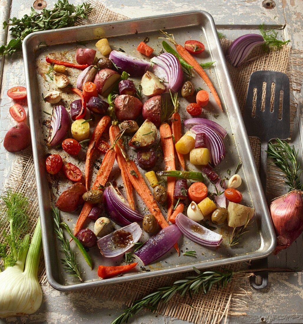 Roasted root vegetables with rosemary on a baking tray