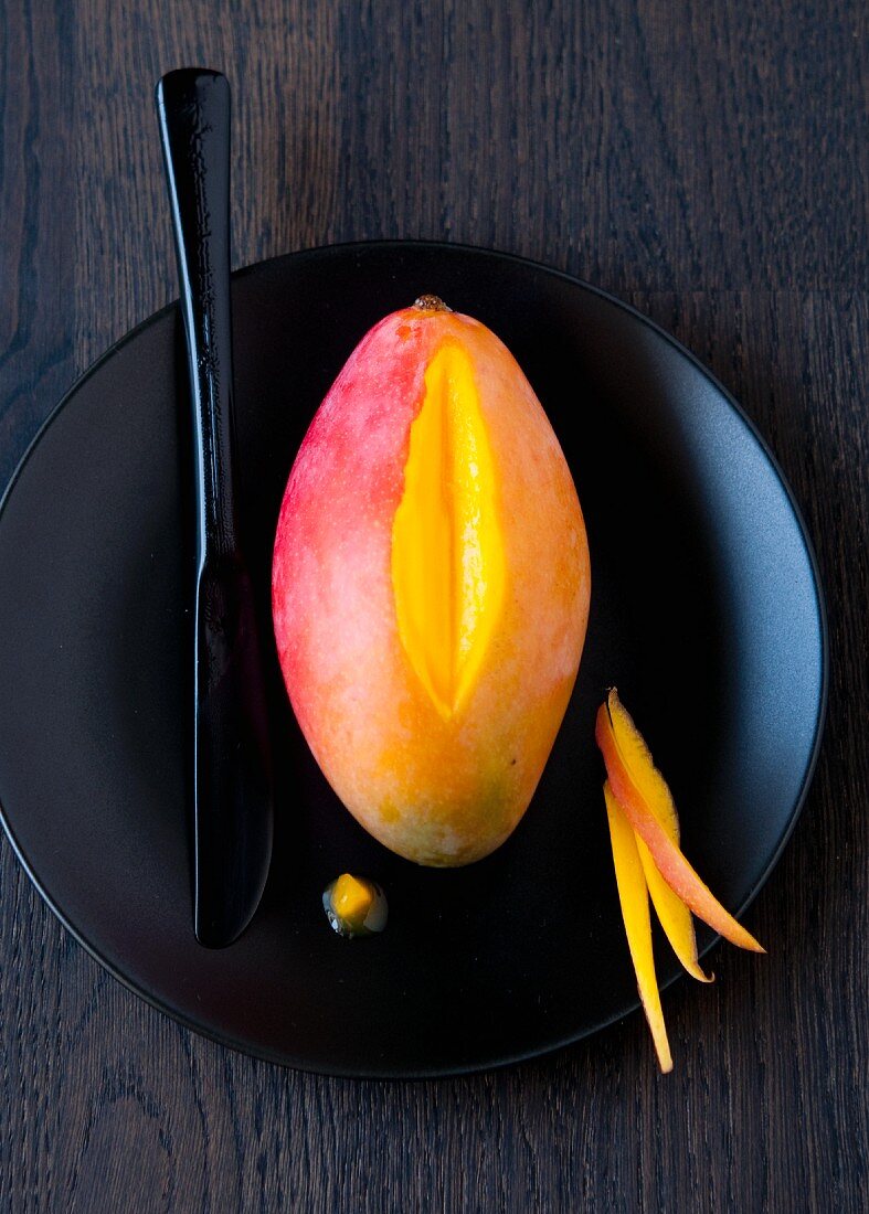 Mango auf schwarzem Teller (angeschnitten)
