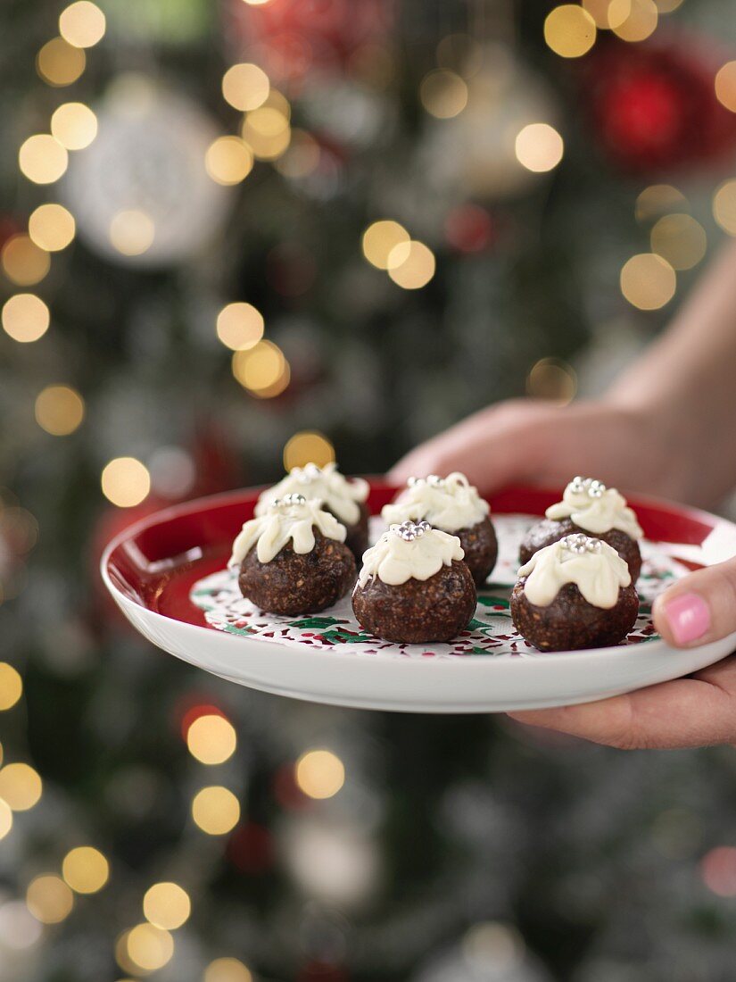 Hands holding a Christmas plate with Christmas pudding truffle pralines
