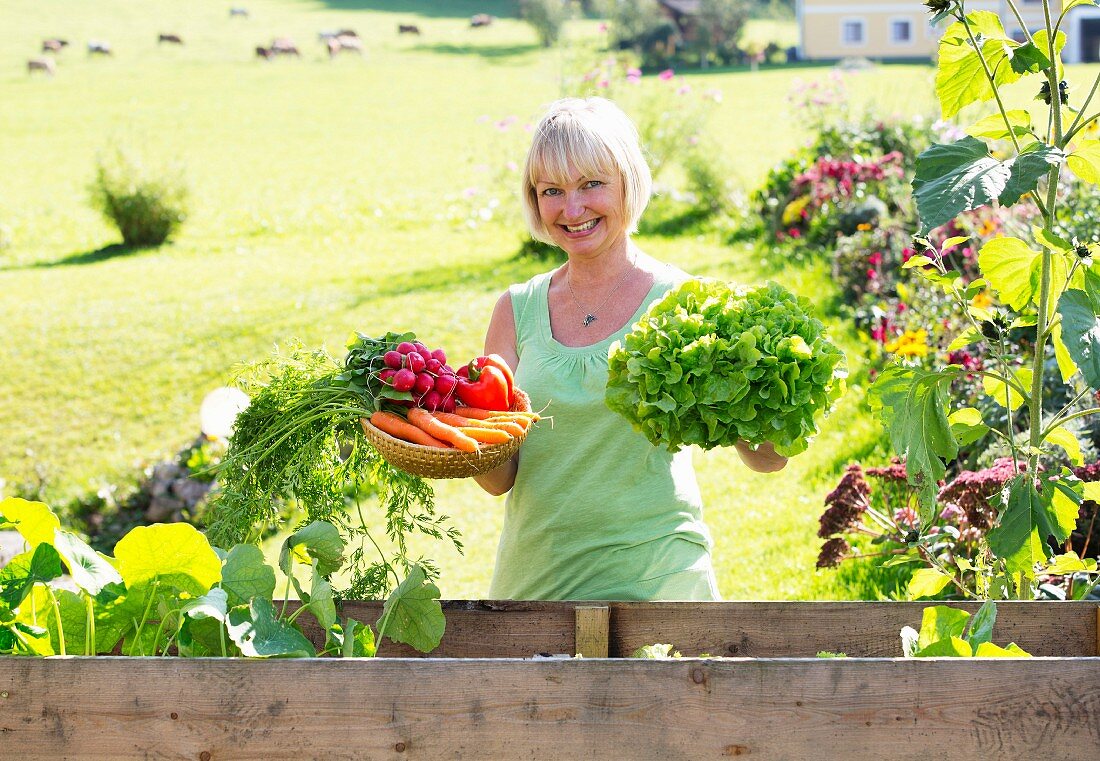 A happy woman showing off her vegetable harvest