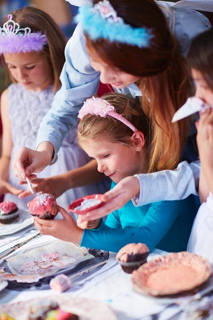 Mädchen verzieren Cupcakes auf einer Geburtstagsparty