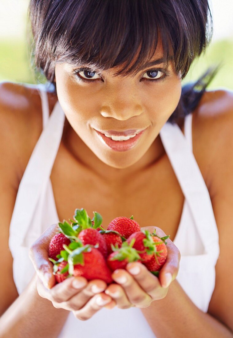 A smiling woman holding strawberries