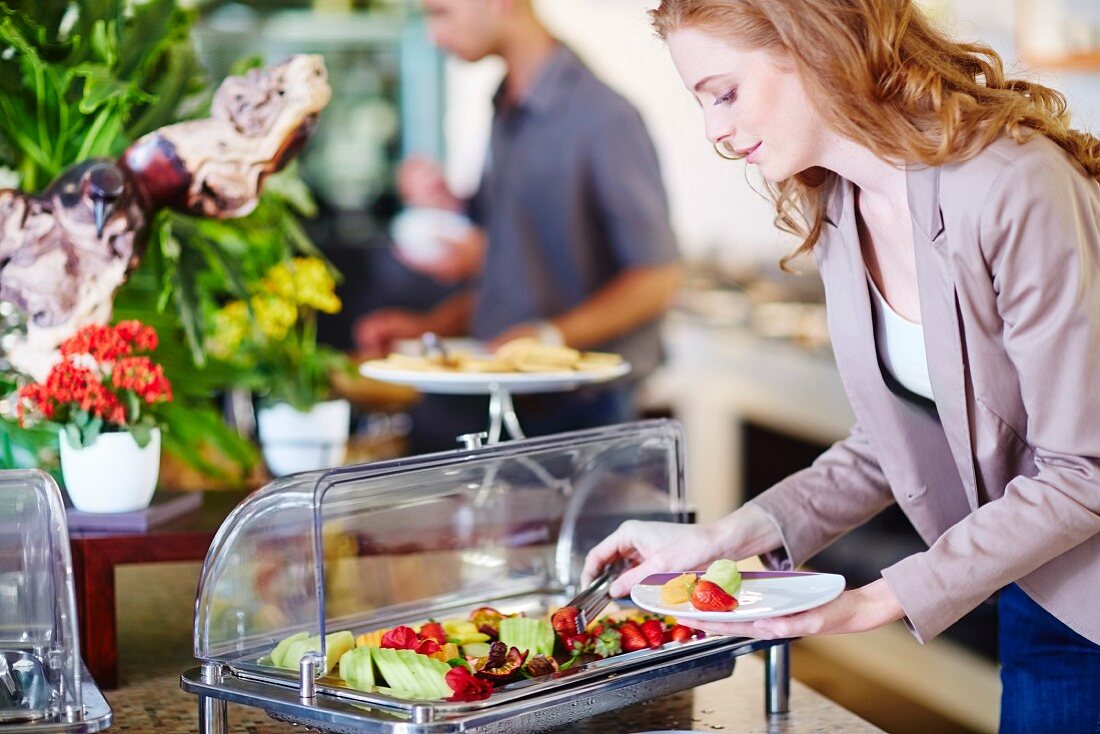 A businesswoman taking fruit from a salad bar