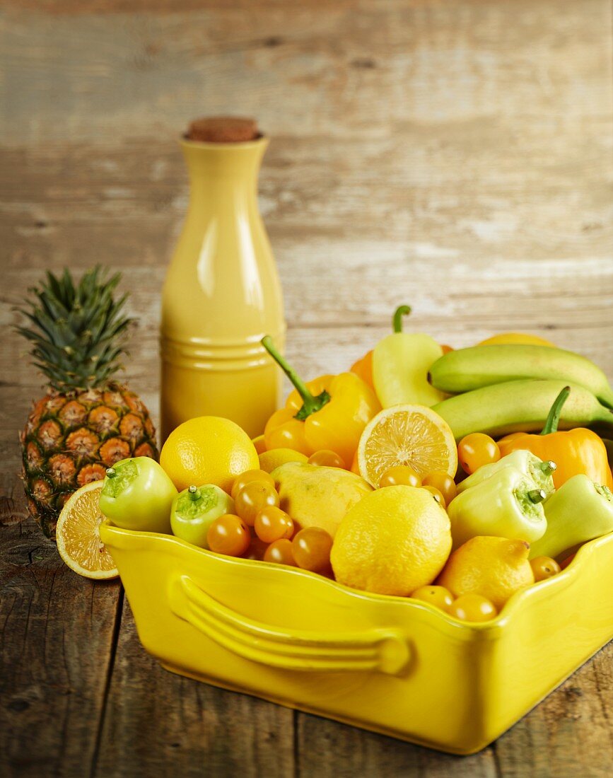 Verschiedene gelbe Früchte und Gemüsesorten in Keramikschale