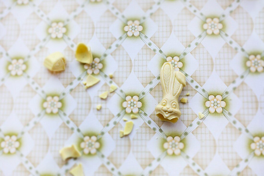 A broken white chocolate bunny on a vintage surface