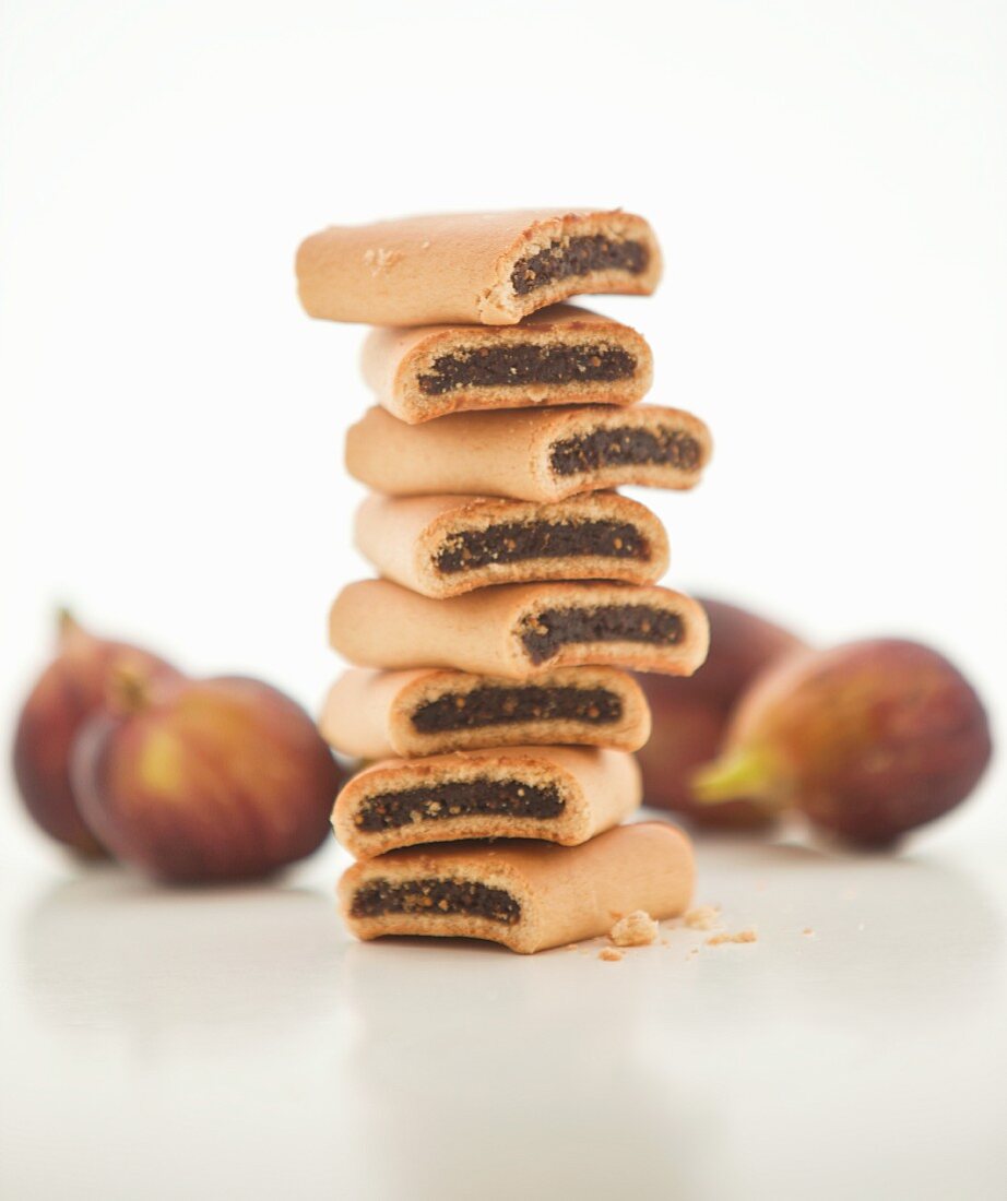 A stack of fig rolls with fresh figs in the background