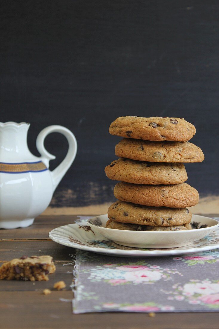 A stack of chocolate chip cookies and a pot of tea