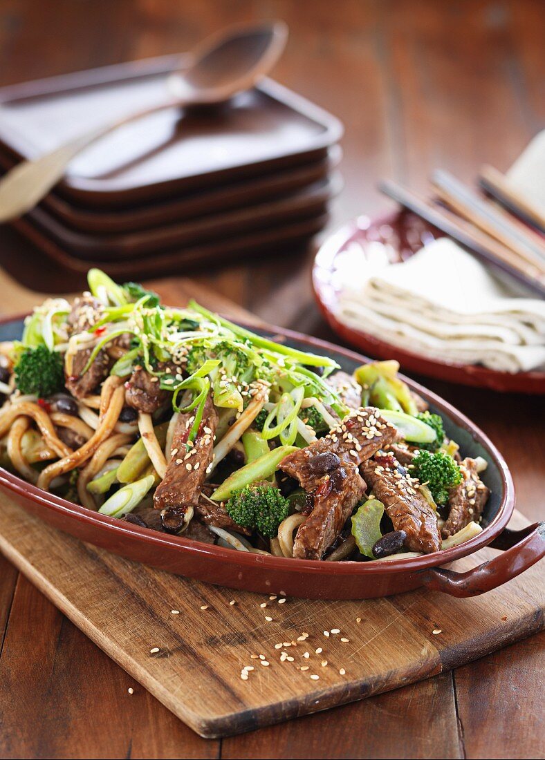 Beef with noodles, sesame seeds, broccoli and spring onions