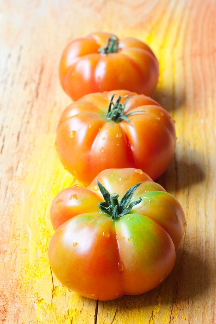 Three Sicilian tomatoes on a wooden surface
