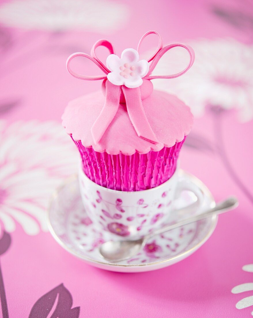 A pink flower cupcake in an espresso cup