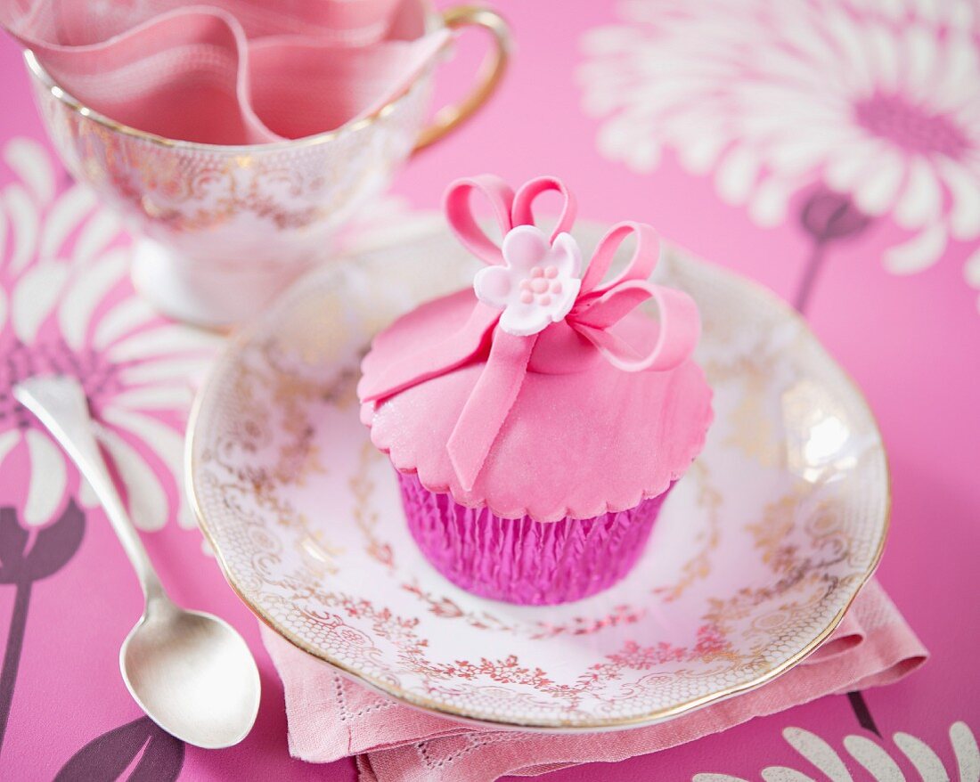 Rosa Blüten-Cupcake auf goldverziertem Teller
