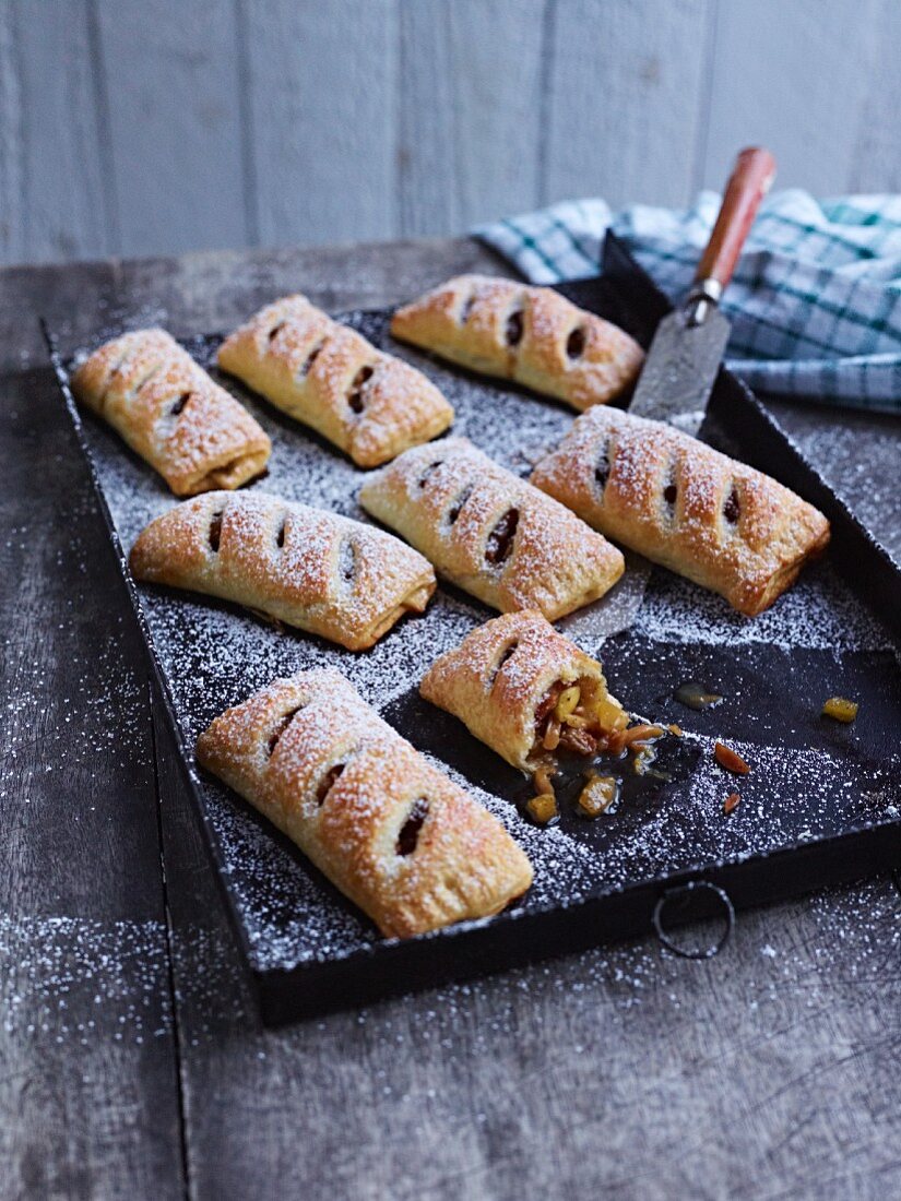 Apple turnovers with icing sugar on a baking tray