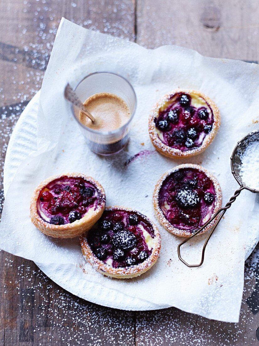 Berry tartlets with icing sugar served with coffee