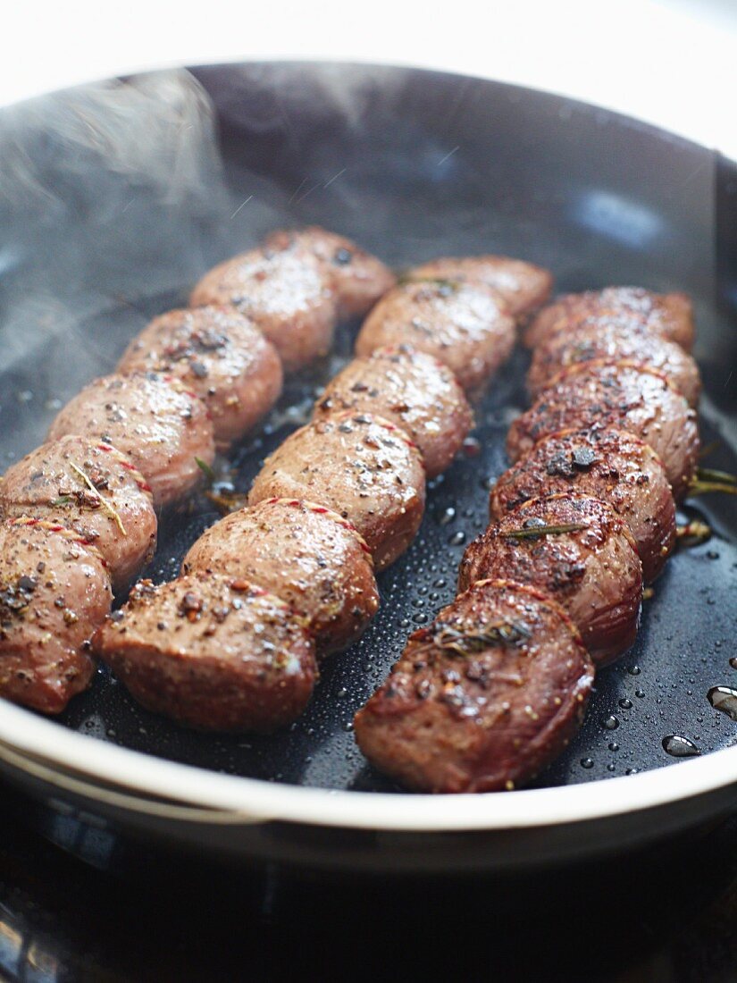 Venison fillets being fried in a pan