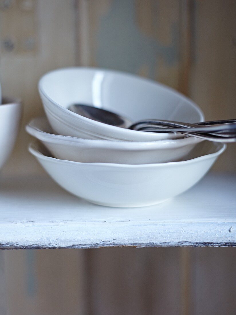 Soup bowls, bowls and spoons on a kitchen shelf