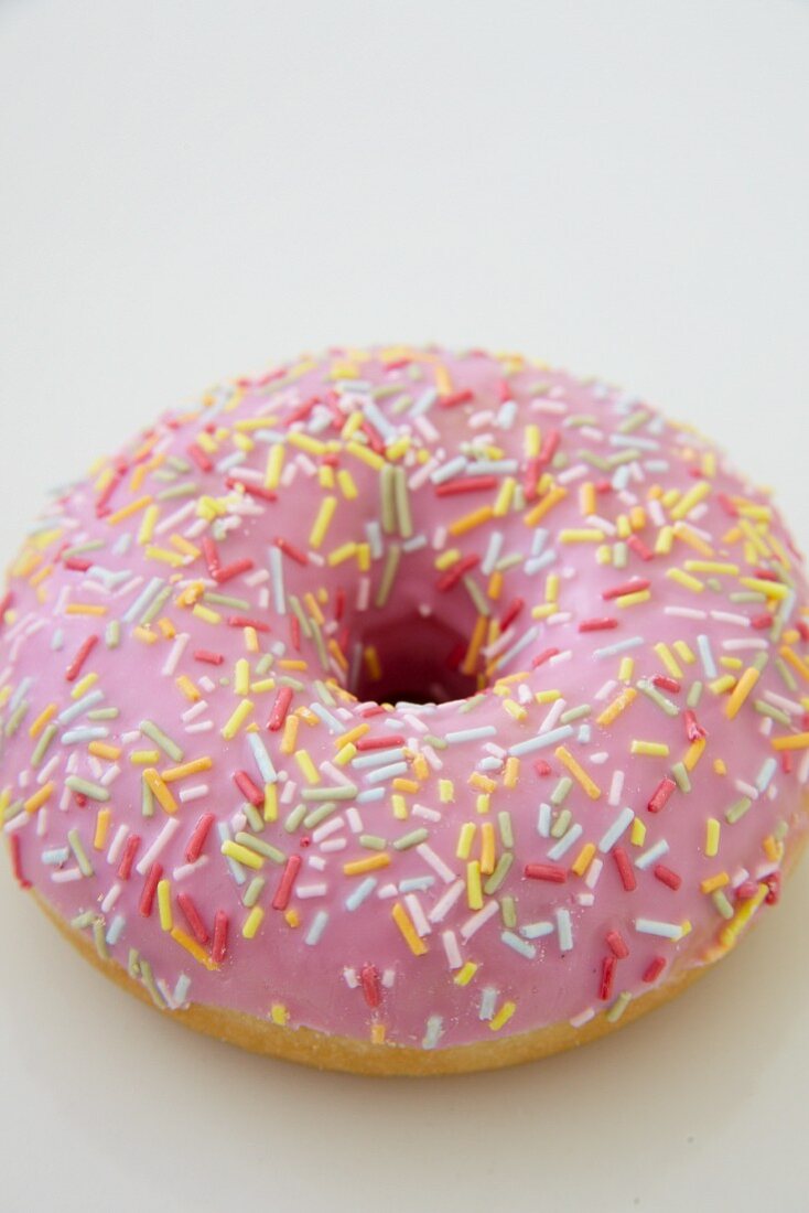 A pink iced doughnut with sugar sprinkles
