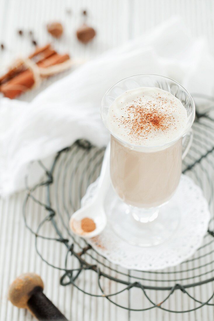 A glass of chai tea latte on a wire rack with whole spices