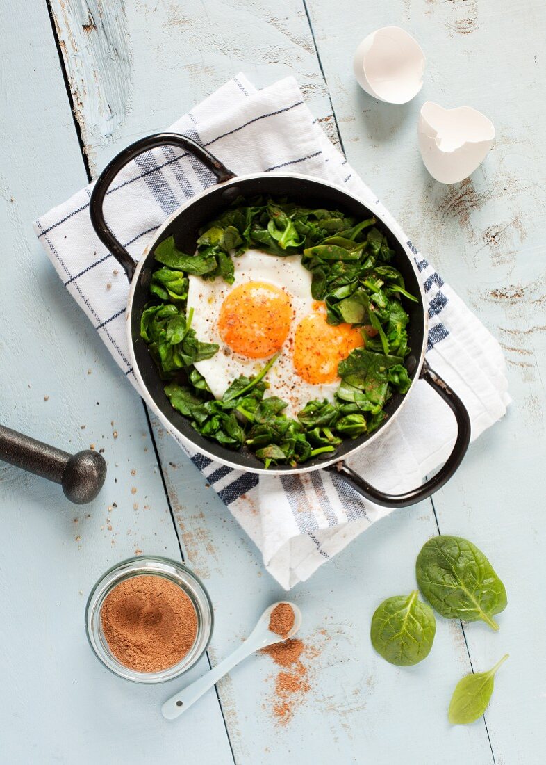 A double yolked egg with nutmeg on a spinach salad (seen from above)