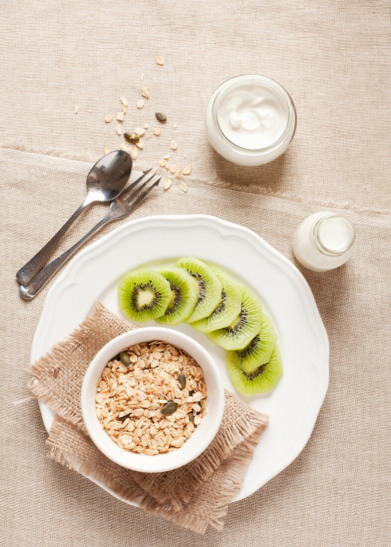 A healthy breakfast of oats, pumpkin seeds, milk, yoghurt and kiwis