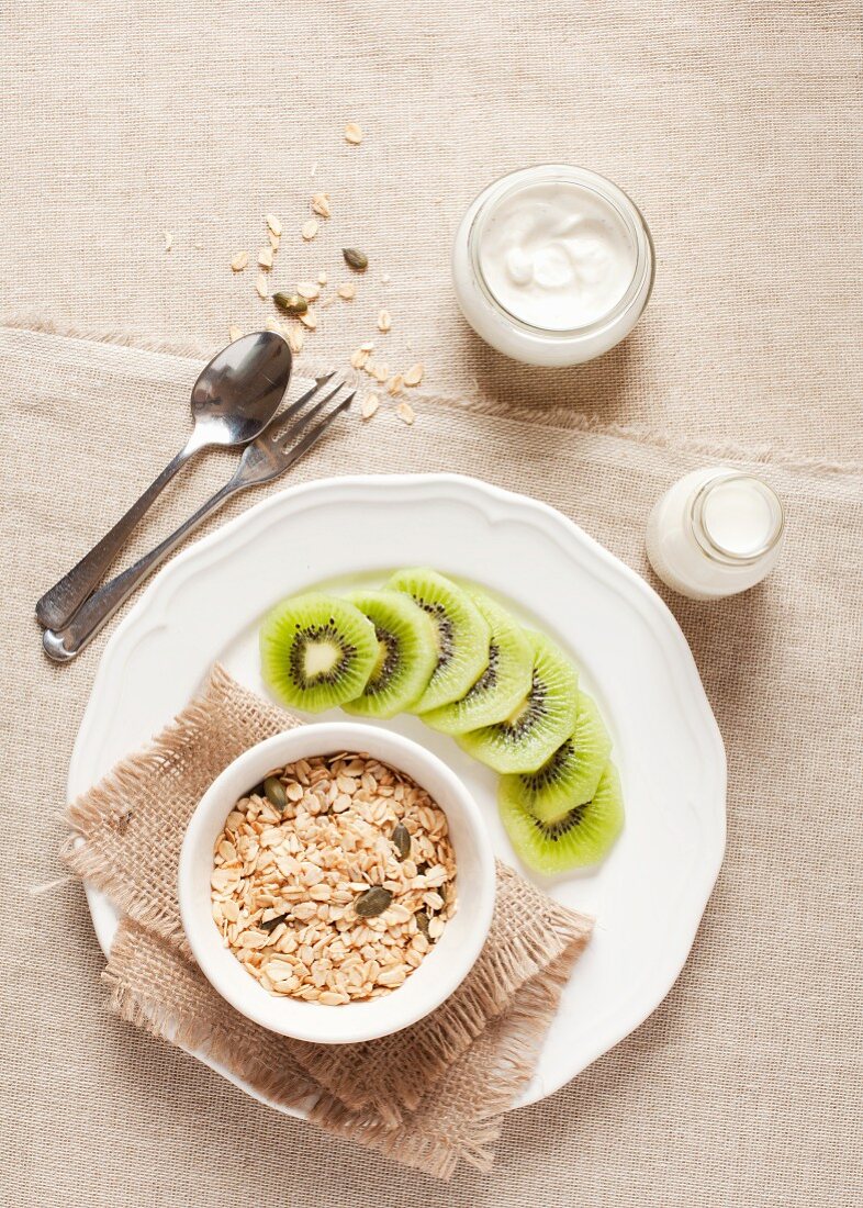Gesundes Frühstück mit Haferflocken, Kürbiskernen, Milch, Joghurt und Kiwi